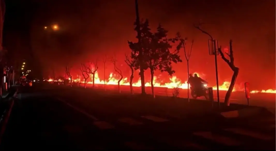 তেহরানের তেলের ডিপোতে ইসরায়েলি বিমান হামলার পর বড় আকারে আগুন ছড়িয়ে পড়ে। এই নারকীয় পরিস্থিতির মধ্যেই এক ব্যক্তি বাইক ছুটিয়েছেন সড়কে। ছবি: এএফপি